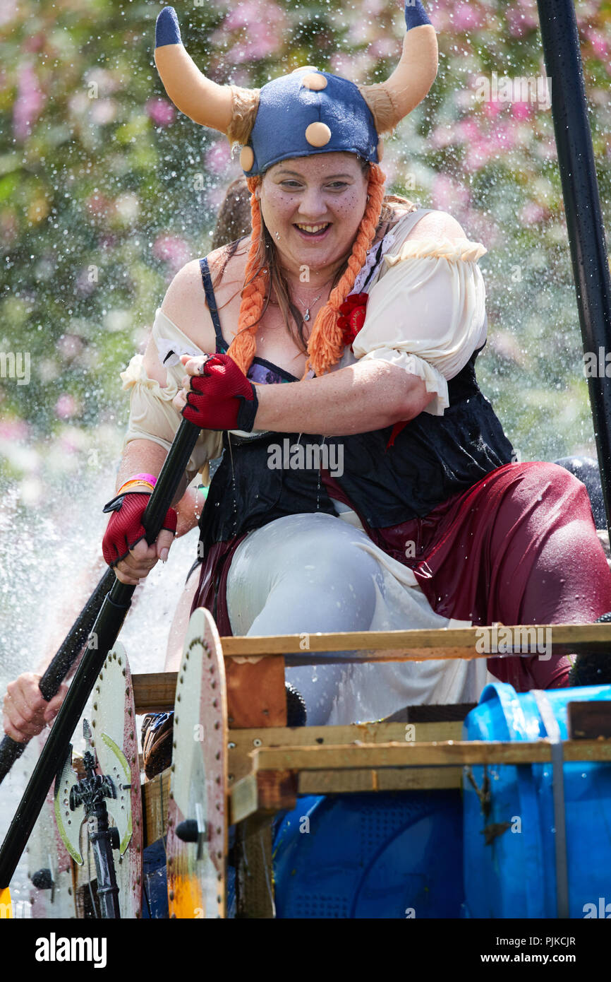 Woman rowing un radeau le long d'une rivière dans un costume de viking à La Plaine des jeux, Thorney, Somerset, Angleterre Banque D'Images