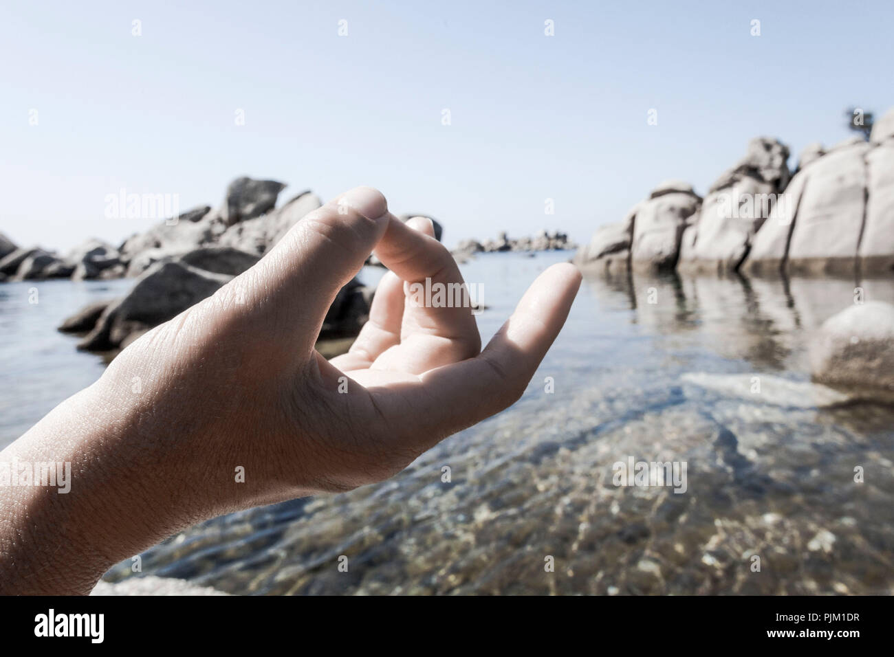 La méditation, le geste de la main sur la plage rocheuse en face de mer Banque D'Images