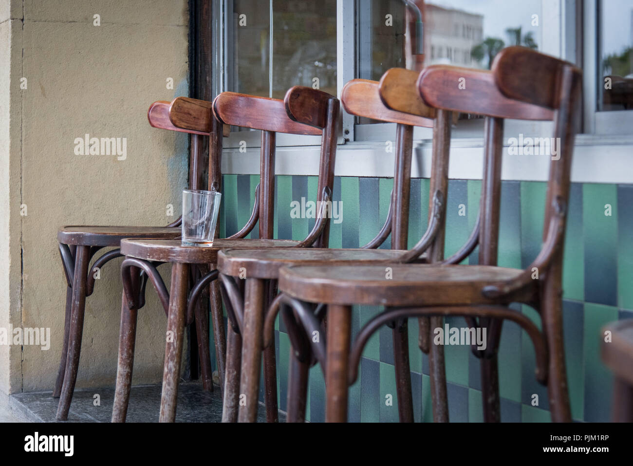 Impressions depuis les rues de Barcelone, 4 chaises en bois en face d'un café de la rue avec un verre vide Banque D'Images