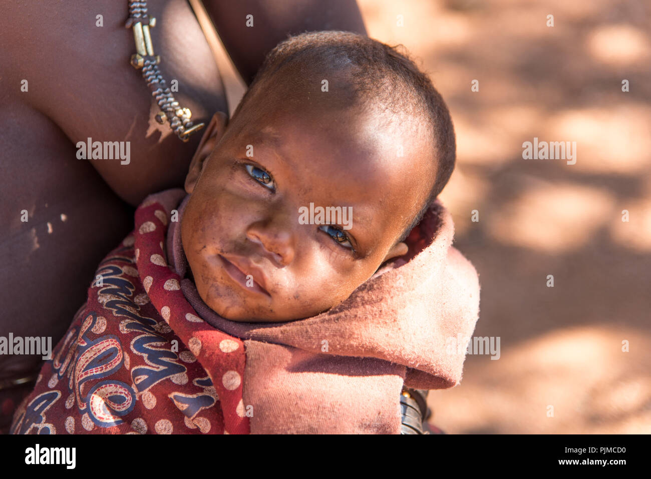 Himba bébé sur le bras de la mère, à la recherche dans l'appareil photo Banque D'Images