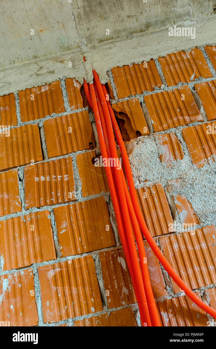 Tubes en plastique orange pour câble électrique accrochée à un mur de  brique dans la maison en construction Photo Stock - Alamy