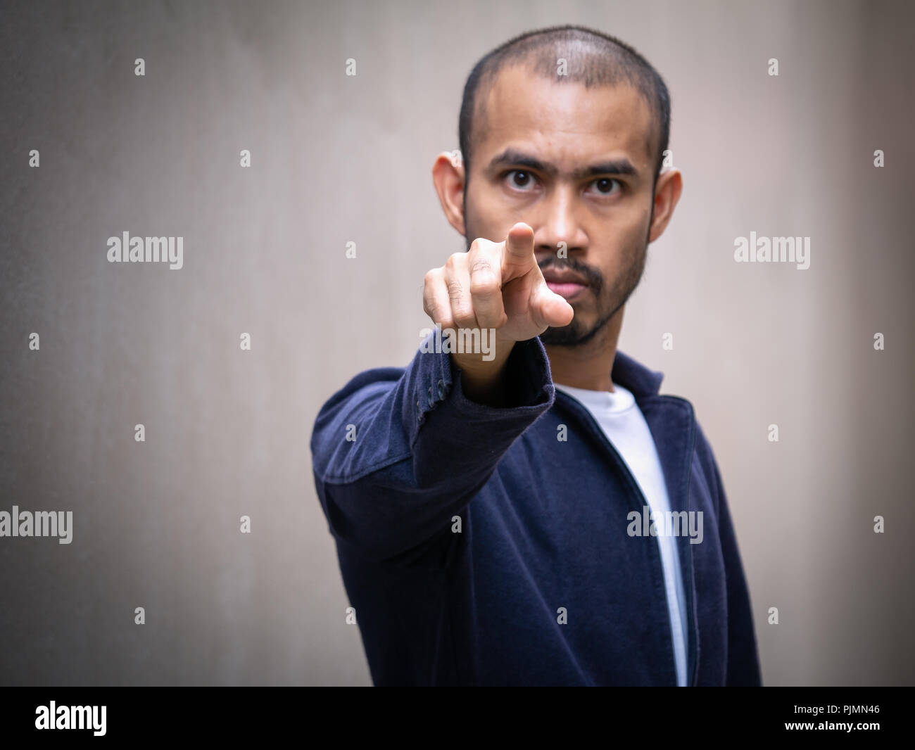 Un homme asiatique portant un maillot bleu points son doigt de l'avant avec une expression de colère. Banque D'Images