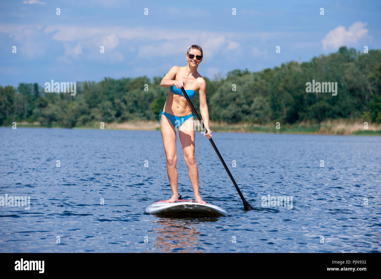 Maillot femme confiant debout avec une pagaie sur la planche de surf Banque D'Images