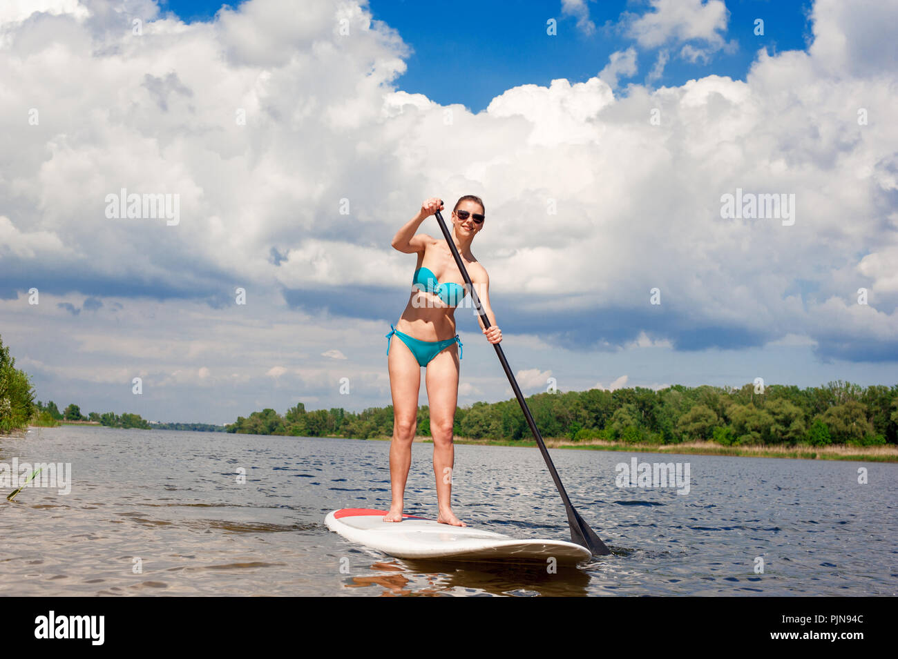 Maillot femme confiant debout avec une pagaie sur la planche de surf Banque D'Images