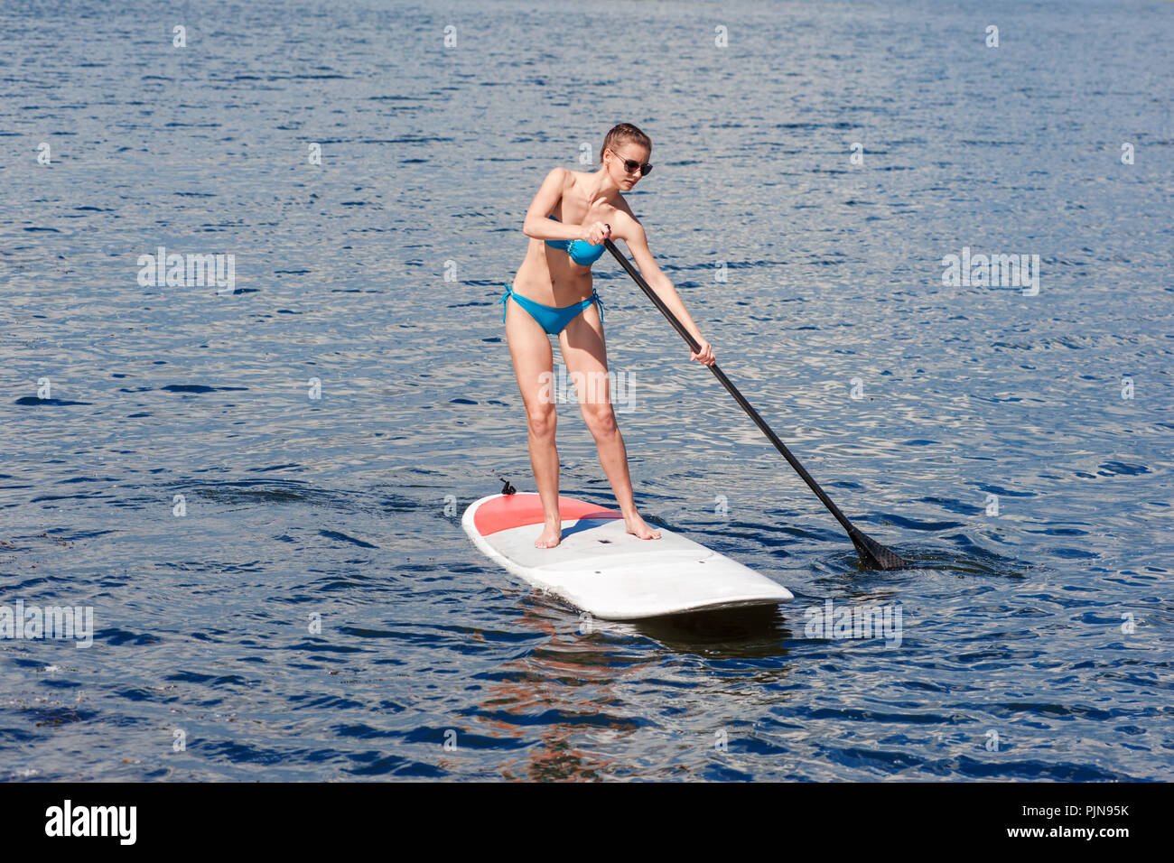 Maillot femme confiant debout avec une pagaie sur la planche de surf Banque D'Images