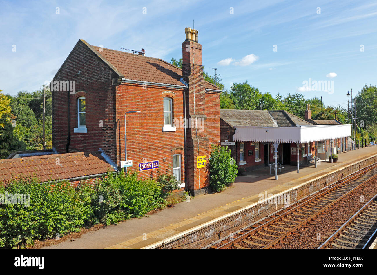 Une vue de la gare sur le Wherry Lignes avec plaques émaillées anciennes toujours en vigueur à Acle, Norfolk, Angleterre, Royaume-Uni, Europe. Banque D'Images