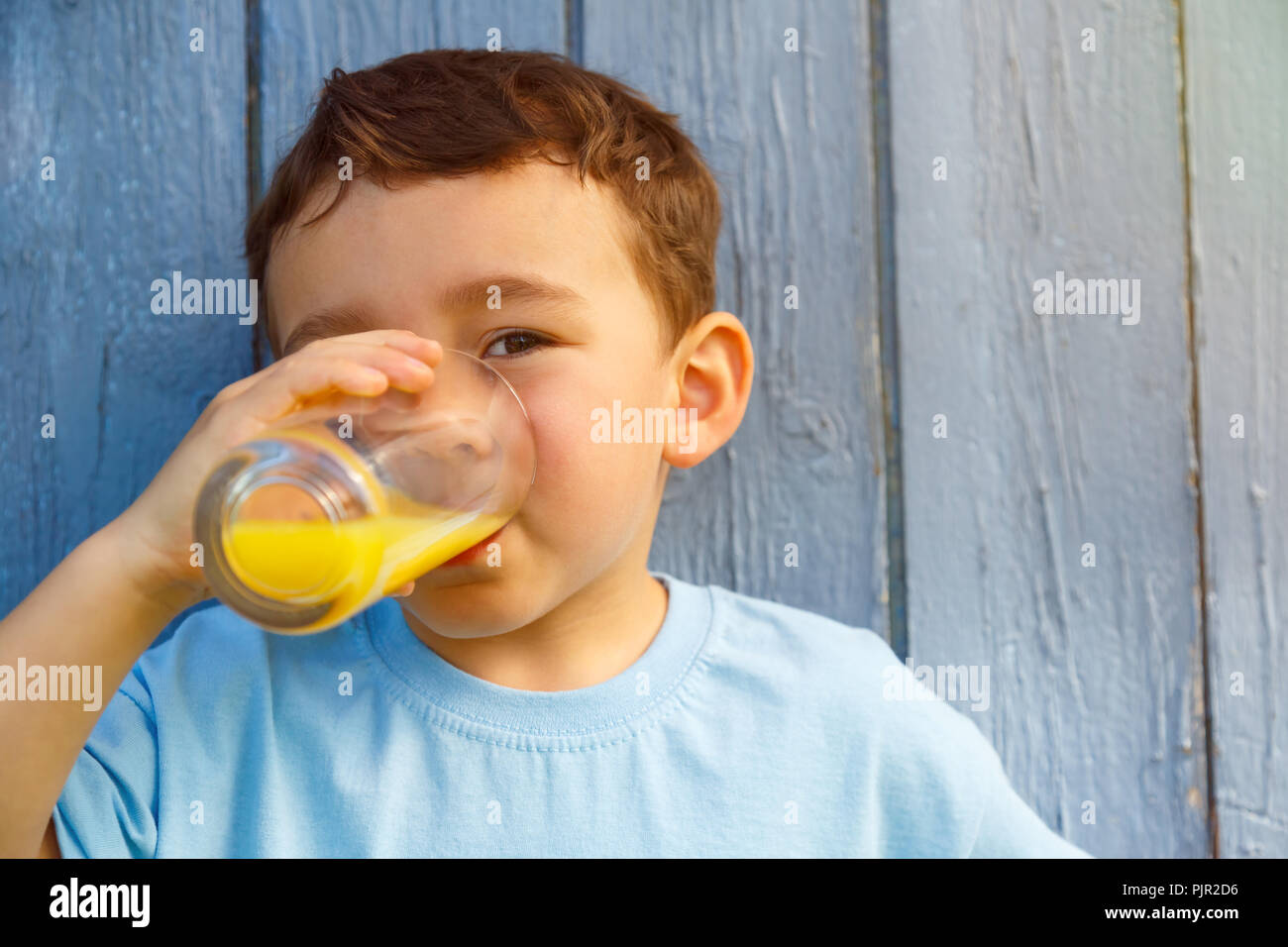 Enfant petit garçon de boire un verre de jus d'orange à l'extérieur de l'espace plein air copyspace copier l'extérieur verre Banque D'Images