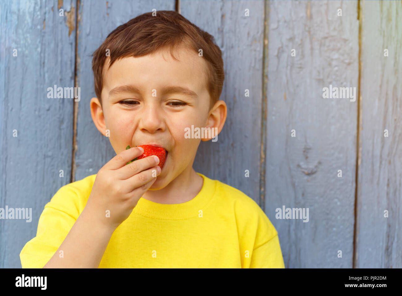 Enfant kid little boy eating strawberry fruit fraises d'été copyspace copie espace piscine en plein air à l'extérieur de printemps Banque D'Images