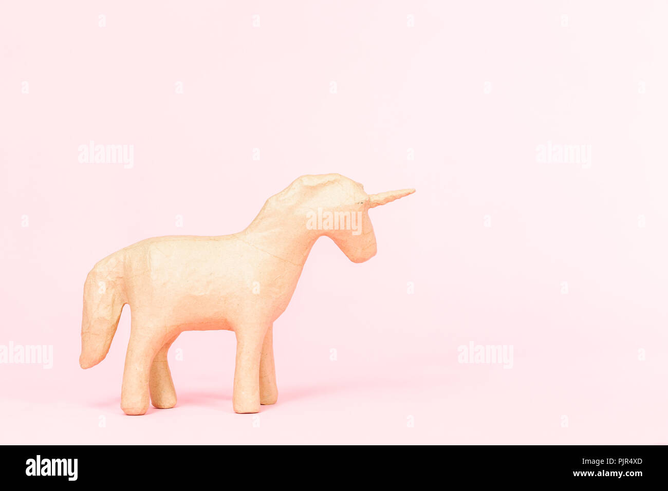 Figurine en papier mâché inachevé d'unicorn sur fond rose. Banque D'Images