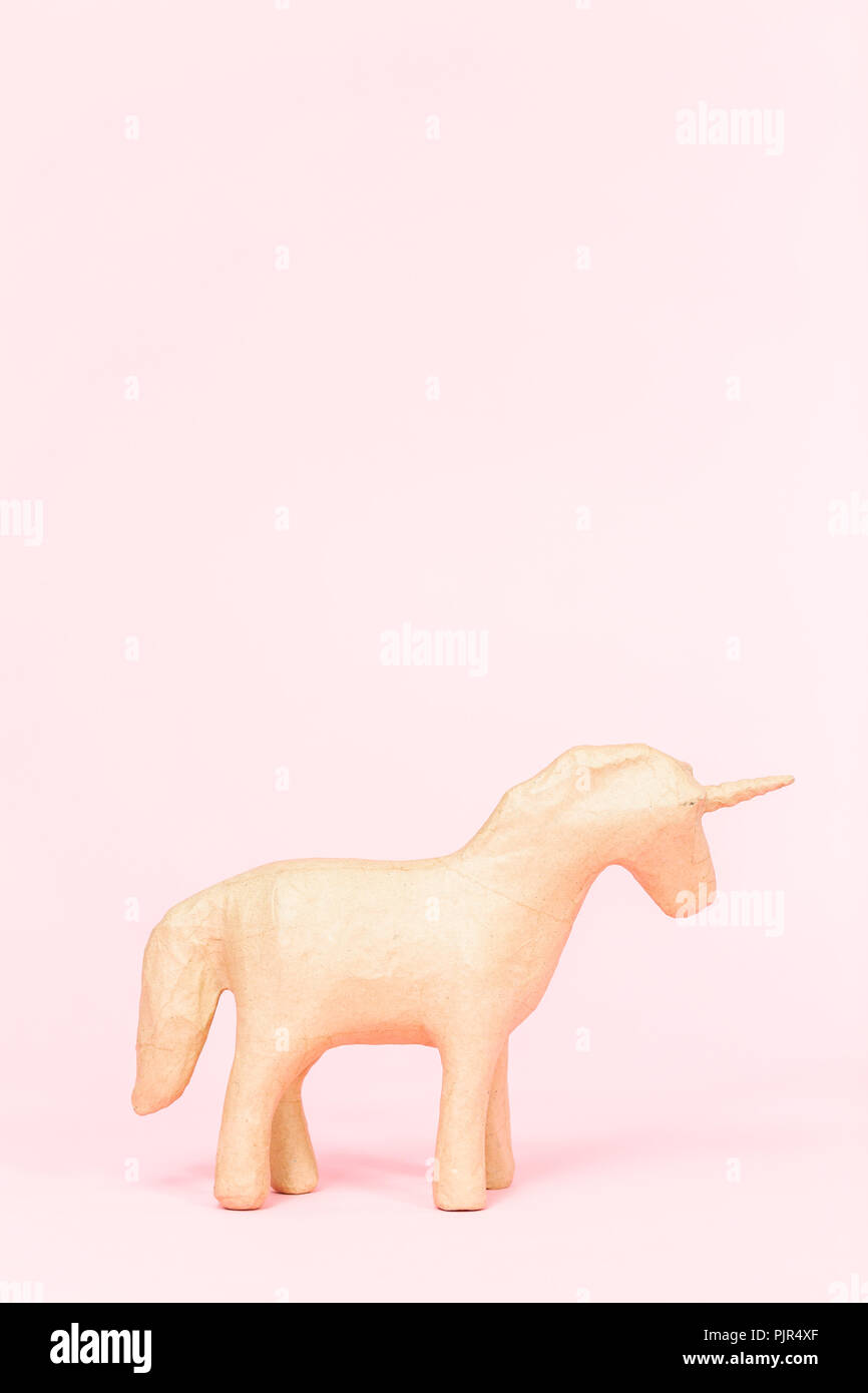 Figurine en papier mâché inachevé d'unicorn sur fond rose. Banque D'Images