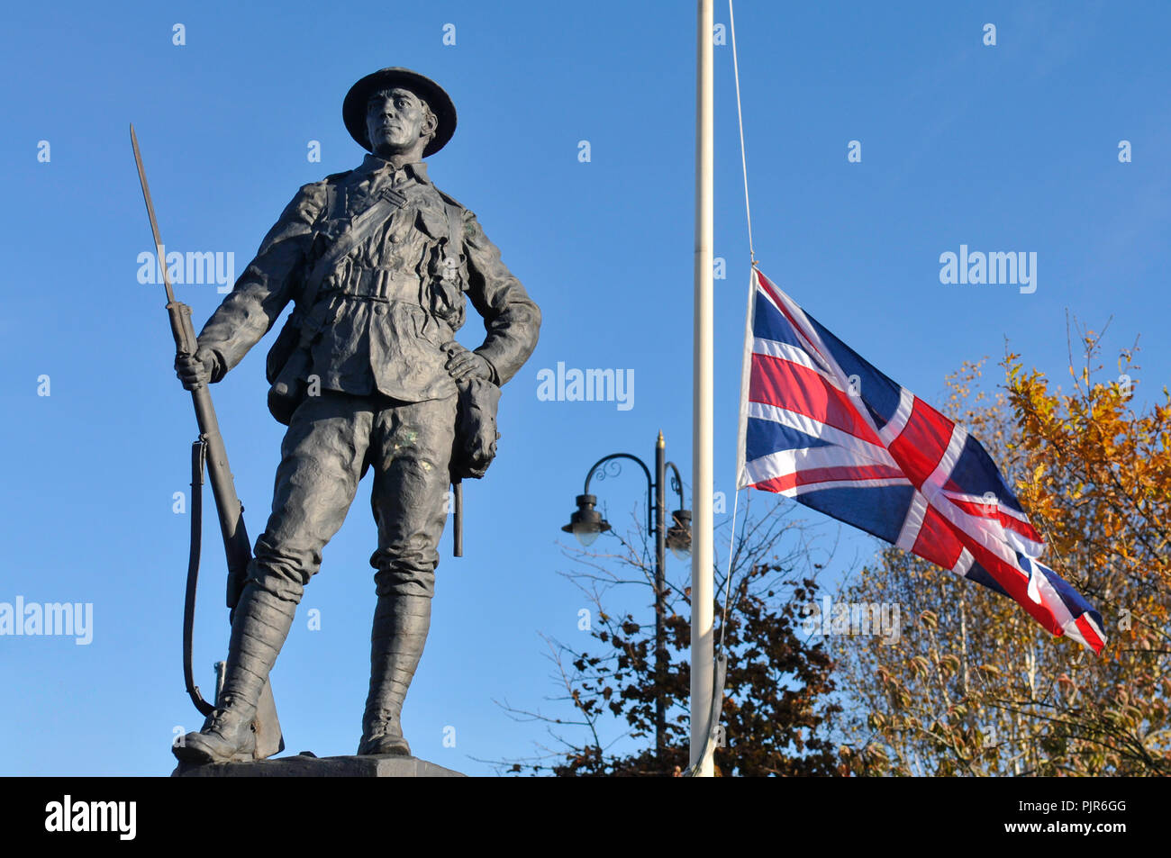 Monument aux soldats tués pendant la Seconde Guerre mondiale 1 a côté d'un mât battant Union Jack drapeau en berne. Banque D'Images