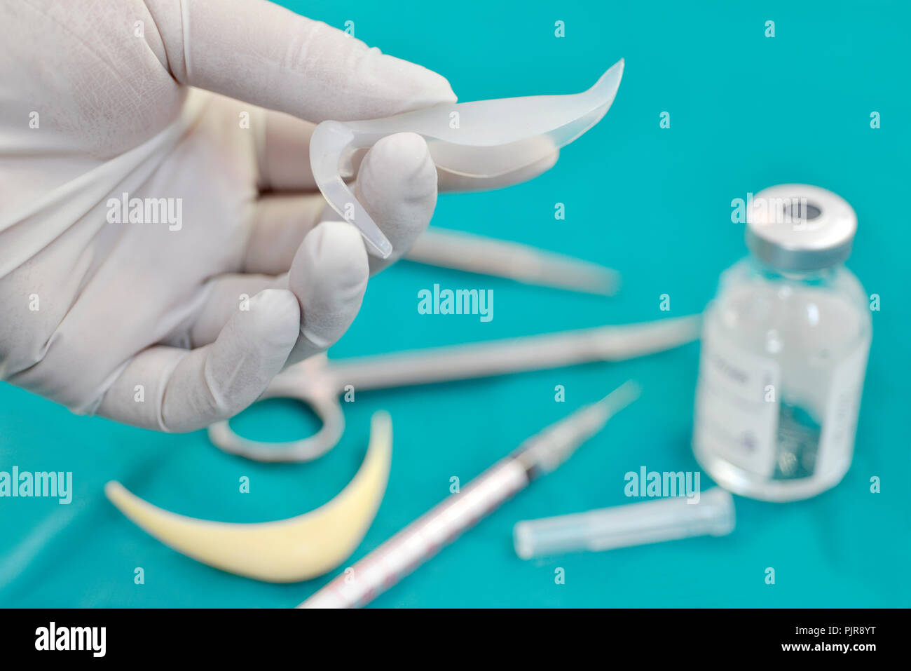 Main tenant le silicone implant nasal en salle d'opération avec le matériel chirurgical et de médicaments. flacon Banque D'Images