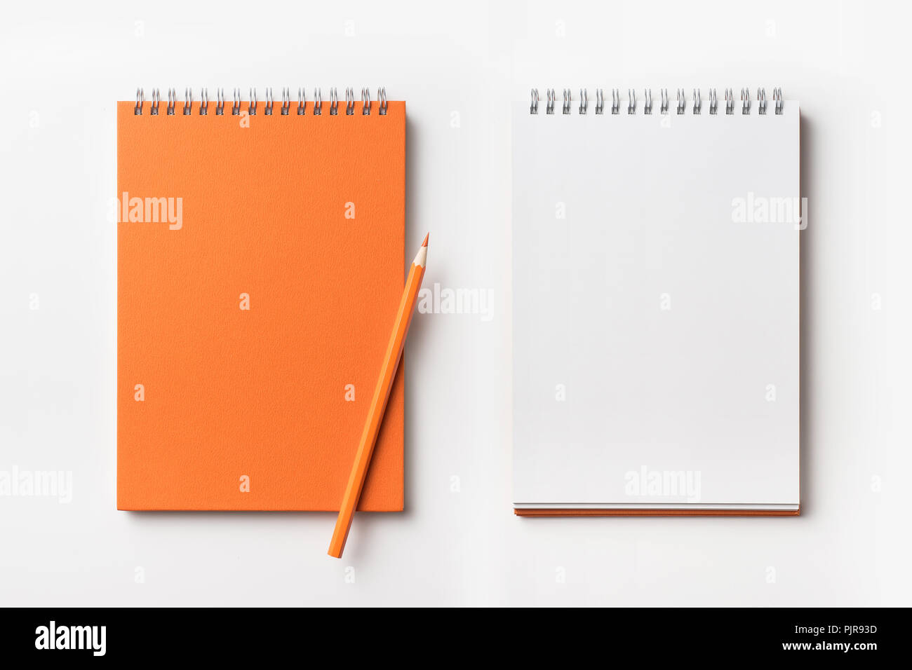 Concept design - Vue de dessus d'orange carnet à spirales et crayon de couleur collection isolé sur fond blanc pour une maquette Banque D'Images