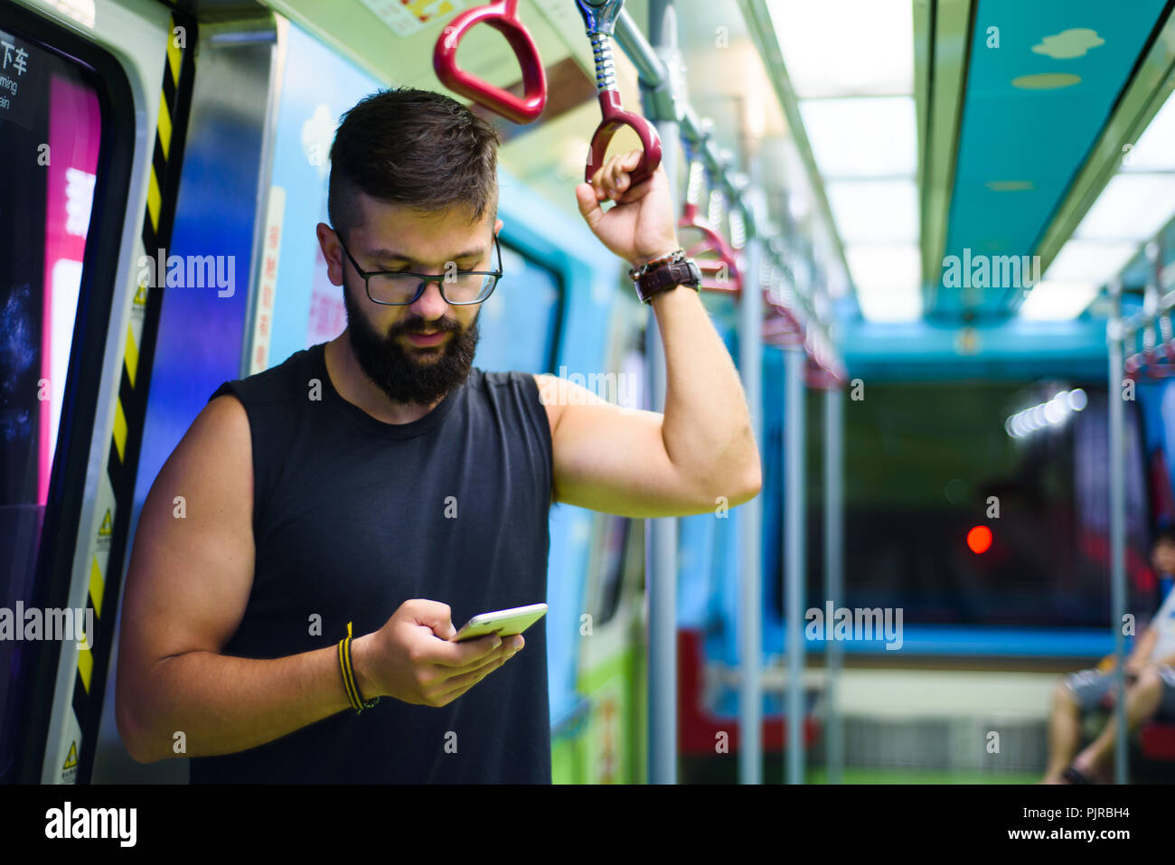 L'homme à l'aide de smart phone tout en prenant le métro Banque D'Images