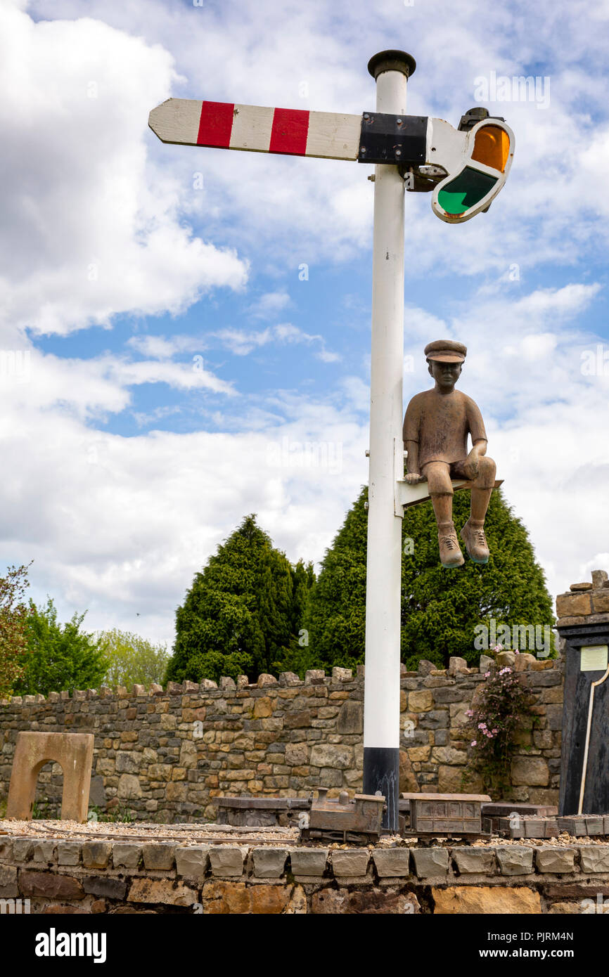 L'Irlande, Co Leitrim, Dromod, centre du village, de la sculpture avec jeune garçon assis sur le signal Banque D'Images