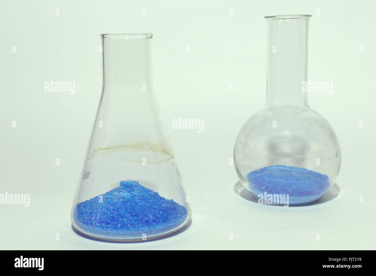 Verrerie de laboratoire avec poudre cristalline bleu vif. substance conique à l'avant du ballon rond vert d'origines. Banque D'Images