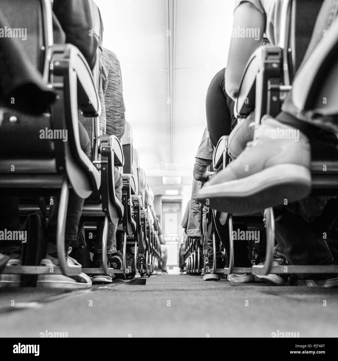 Vue d'agle faible passenegers avion allée avec passenegers assis sur leurs sièges, tandis que l'avion. Photo en noir et blanc. Banque D'Images
