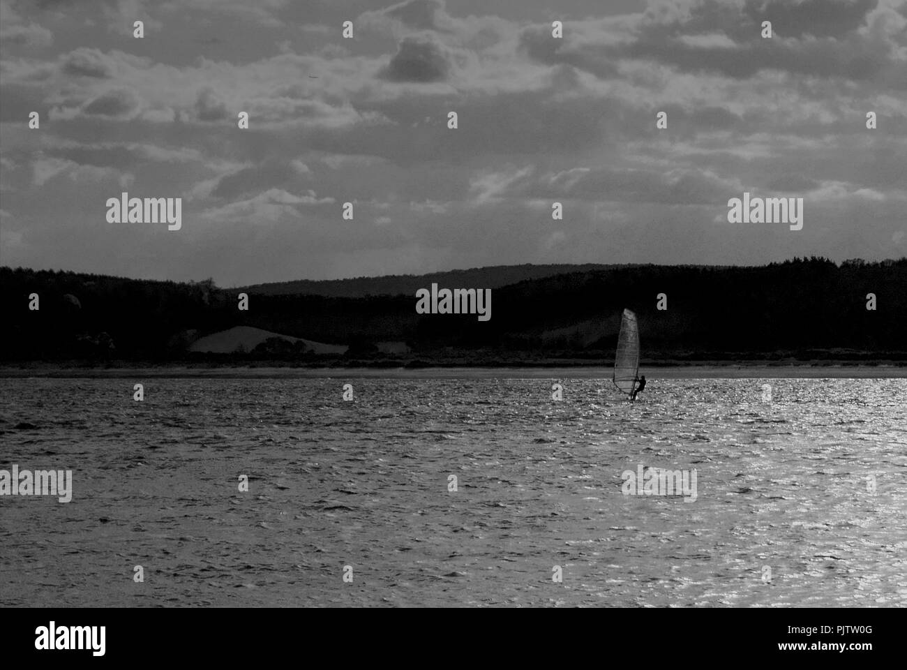 Un surfeur vent prend la dernière course de la journée sur l'estuaire Exe à Exmouth Devon, Angleterre avant que la lumière baisse. Banque D'Images