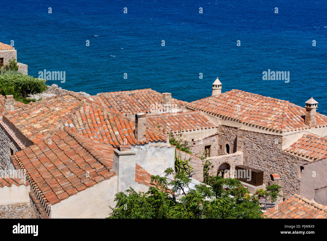 Village côtier traditionnel sur l'île grecque avec des toits en ardoise rouge, de cheminées et de murs en adobe Banque D'Images