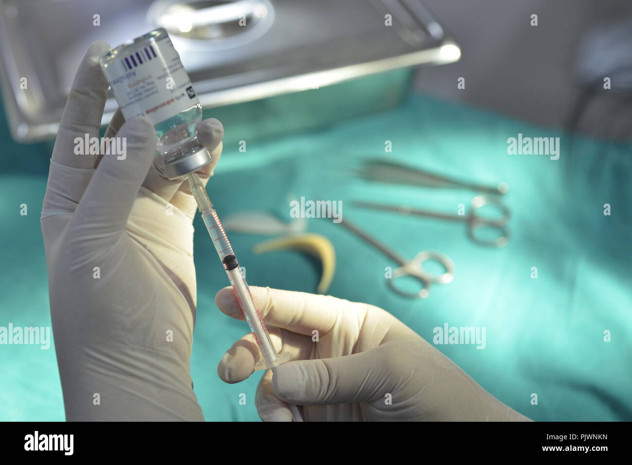 Main tenant la seringue et le flacon de médicament pour préparer l'injection avec le matériel chirurgical et de médicaments de fond du flacon Banque D'Images