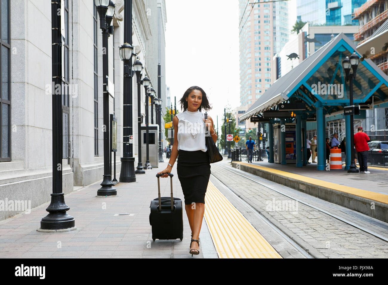 Businesswoman pulling luggage aux côtés de train Banque D'Images