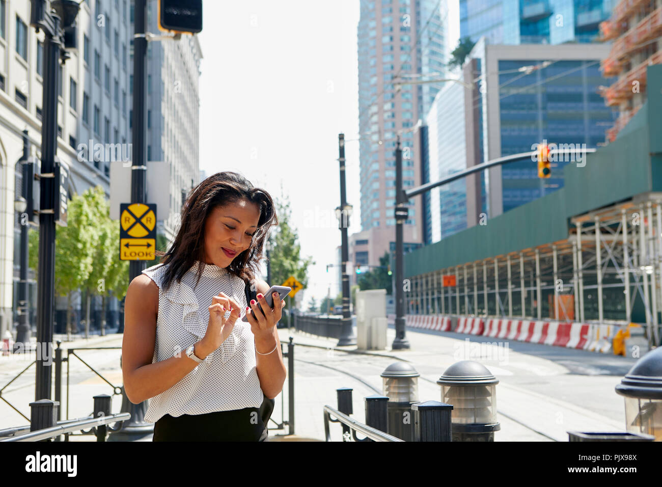 Businesswoman using cellphone par des barrières Banque D'Images