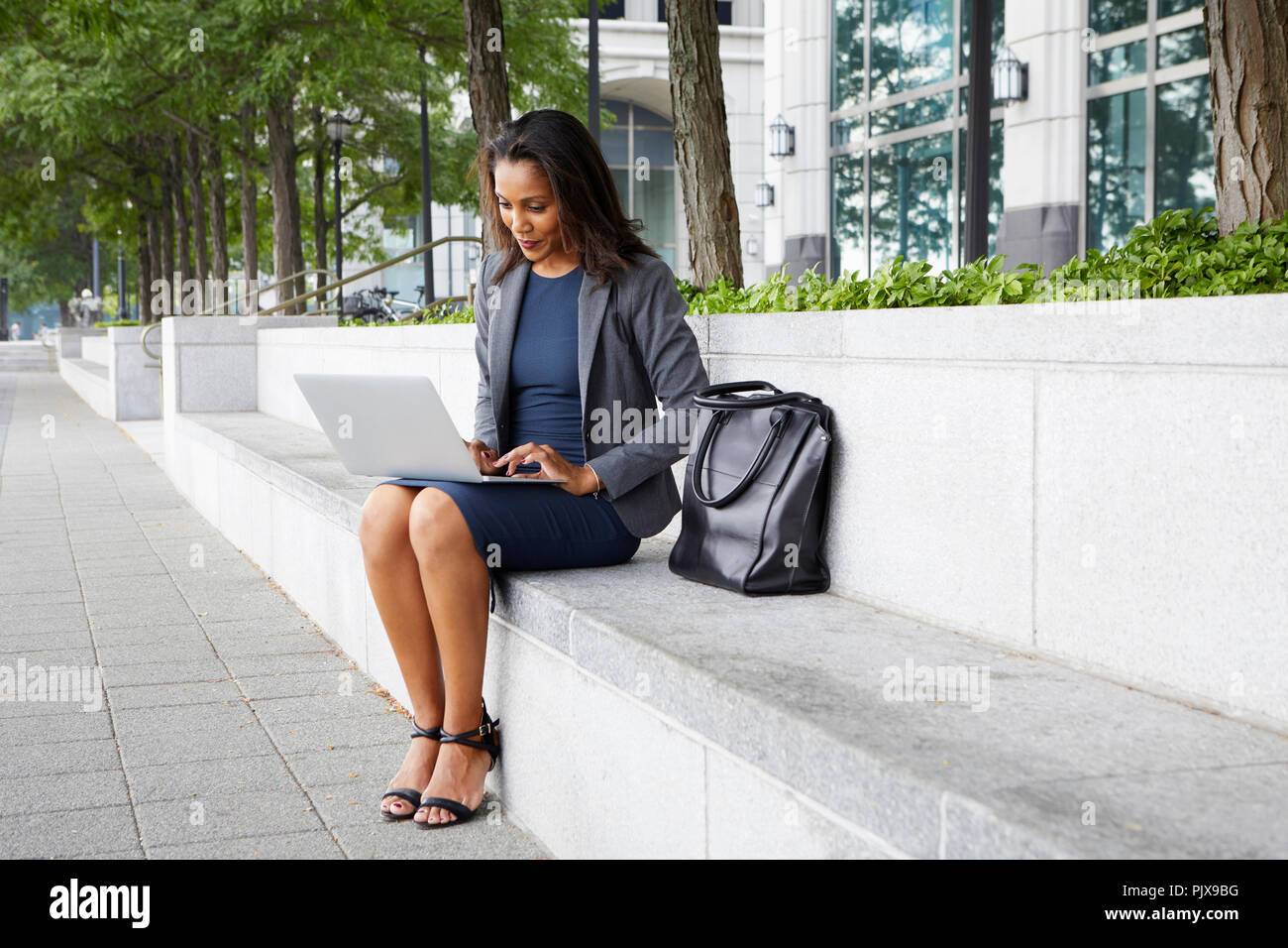 Businesswoman using cellphone and laptop sur coin de rue Banque D'Images