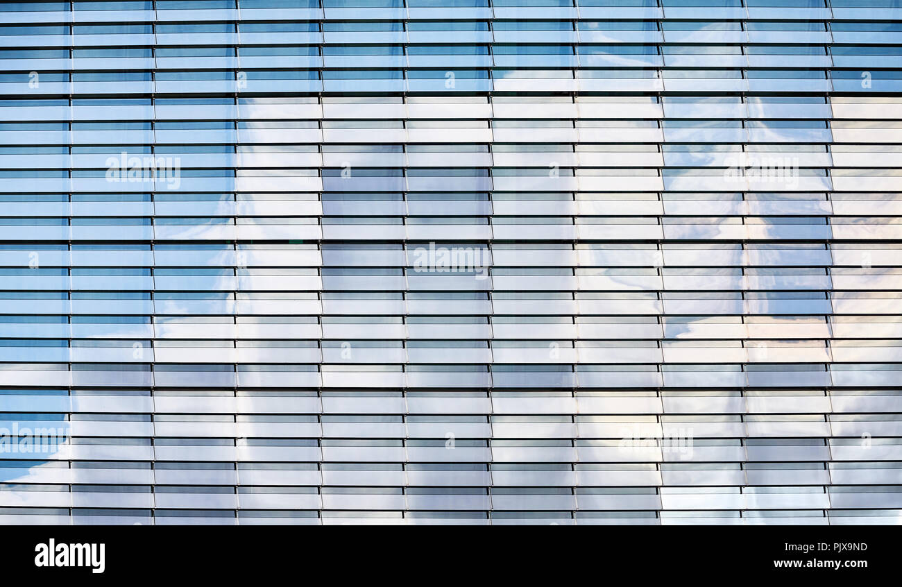 Ciel bleu avec des nuages reflétée dans un bâtiment moderne à la façade de verre, fond architectural moderne. Banque D'Images