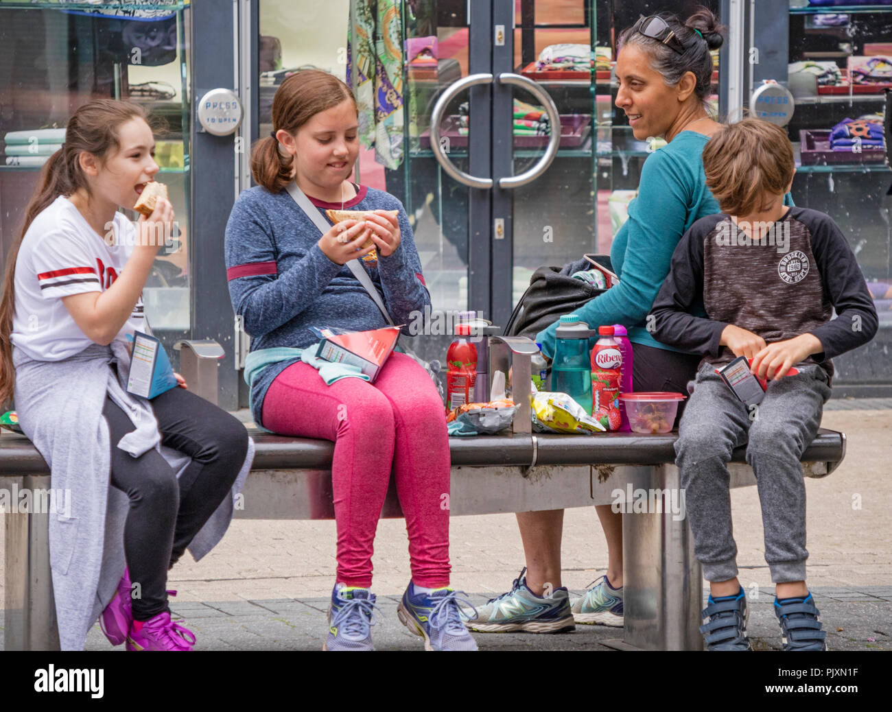 Les enfants mangeant shop acheté restauration rapide tout en faisant du shopping à Bristol, Angleterre, Royaume-Uni Banque D'Images
