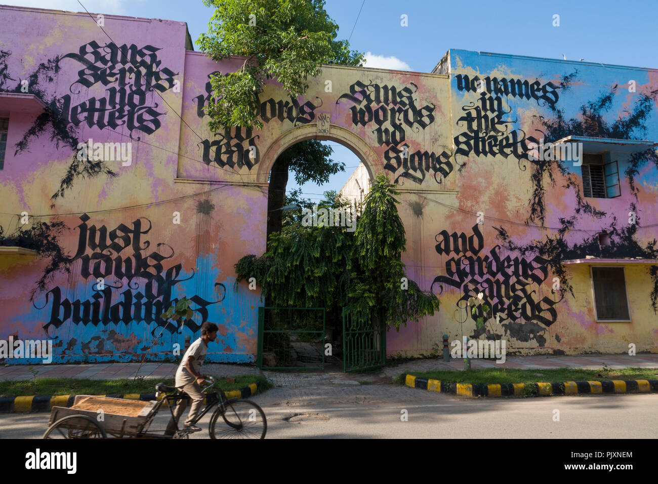 L'homme sur les pédales de pousse-pousse passé street art mural peint par l'artiste néerlandais Niels Shoe Meulman dans Lodhi colony, New Delhi, Inde Banque D'Images