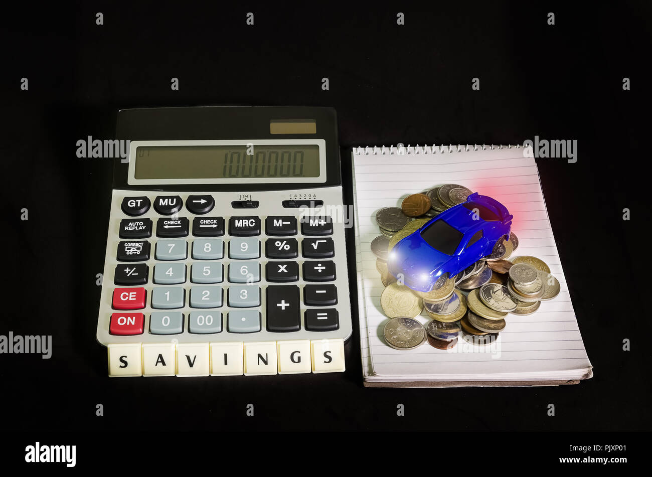 Concept d'économiser de l'argent, une voiture au-dessus de la pile de pièces de monnaie à côté d'une calculatrice Banque D'Images