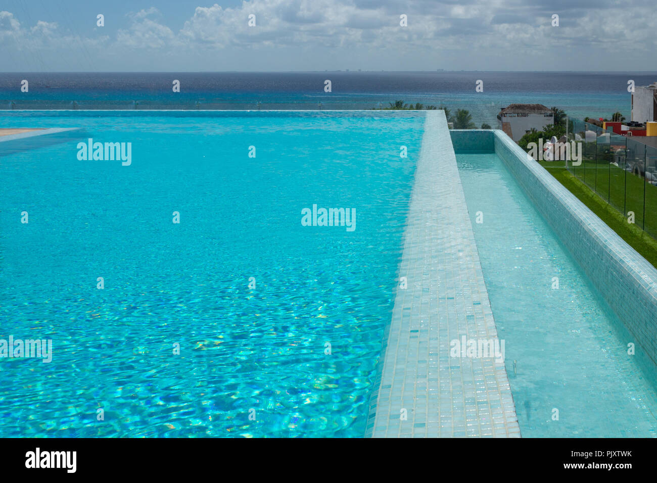 Piscine à débordement sur le toit avec une vue de la Caraïbes. Parasols et chaises longues blanc lui donnent un sens minimaliste où l'protaginist est le point de vue Banque D'Images