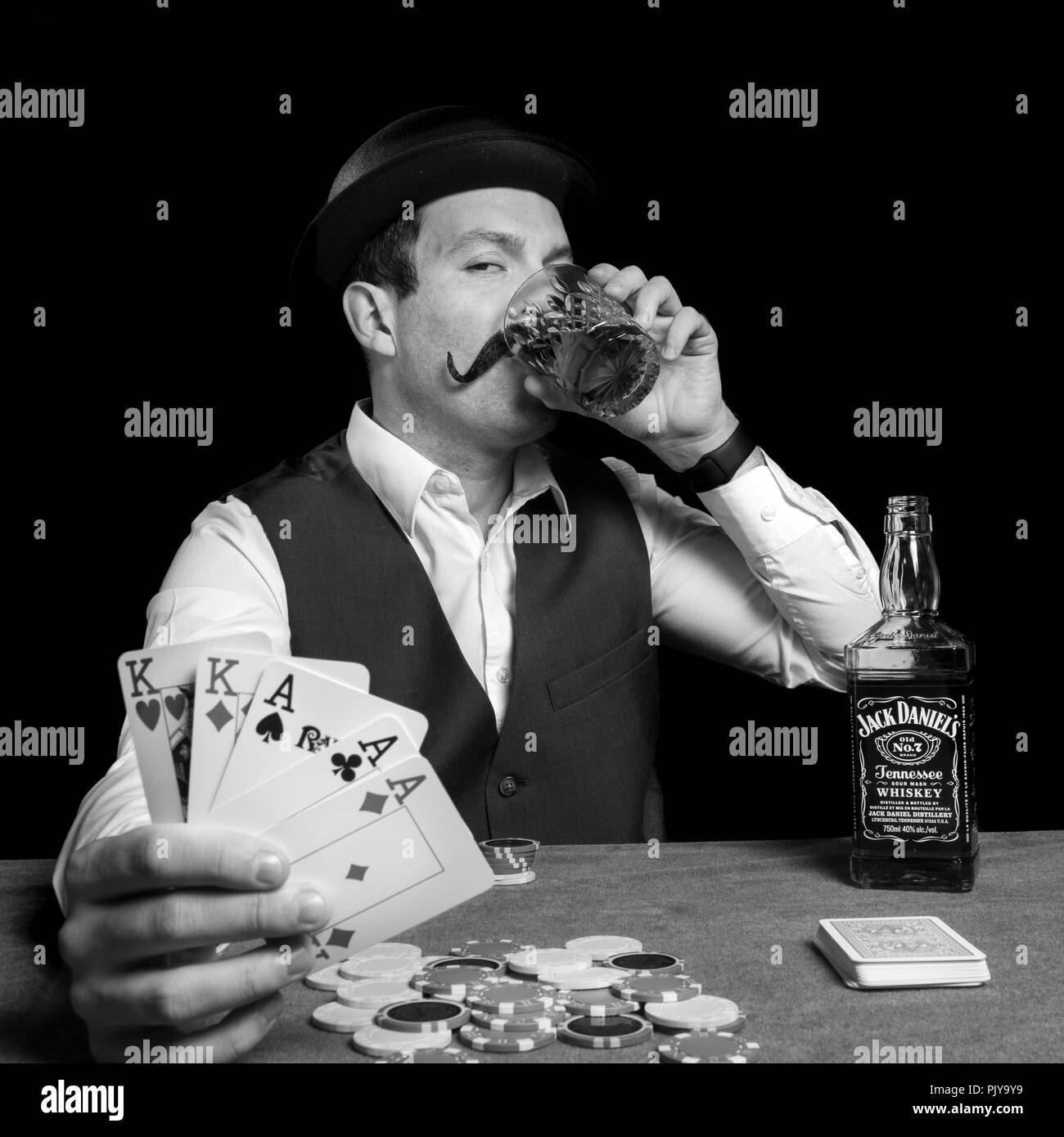 Homme avec chapeau melon de boire de l'alcool et de gagner une partie de poker Jack Daniel's playing cards jeu drôle de faux vintage photography Banque D'Images