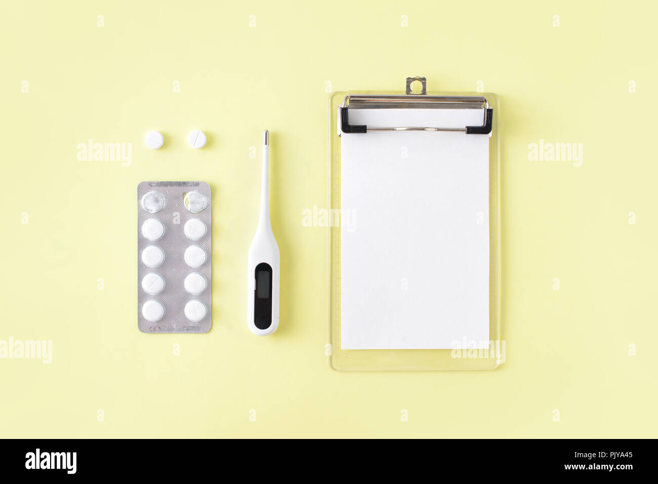 Comprimés, thermomètre et remarque pour la recette sur fond jaune. Le traitement du rhume et de la grippe. Mise à plat, vue du dessus. Banque D'Images