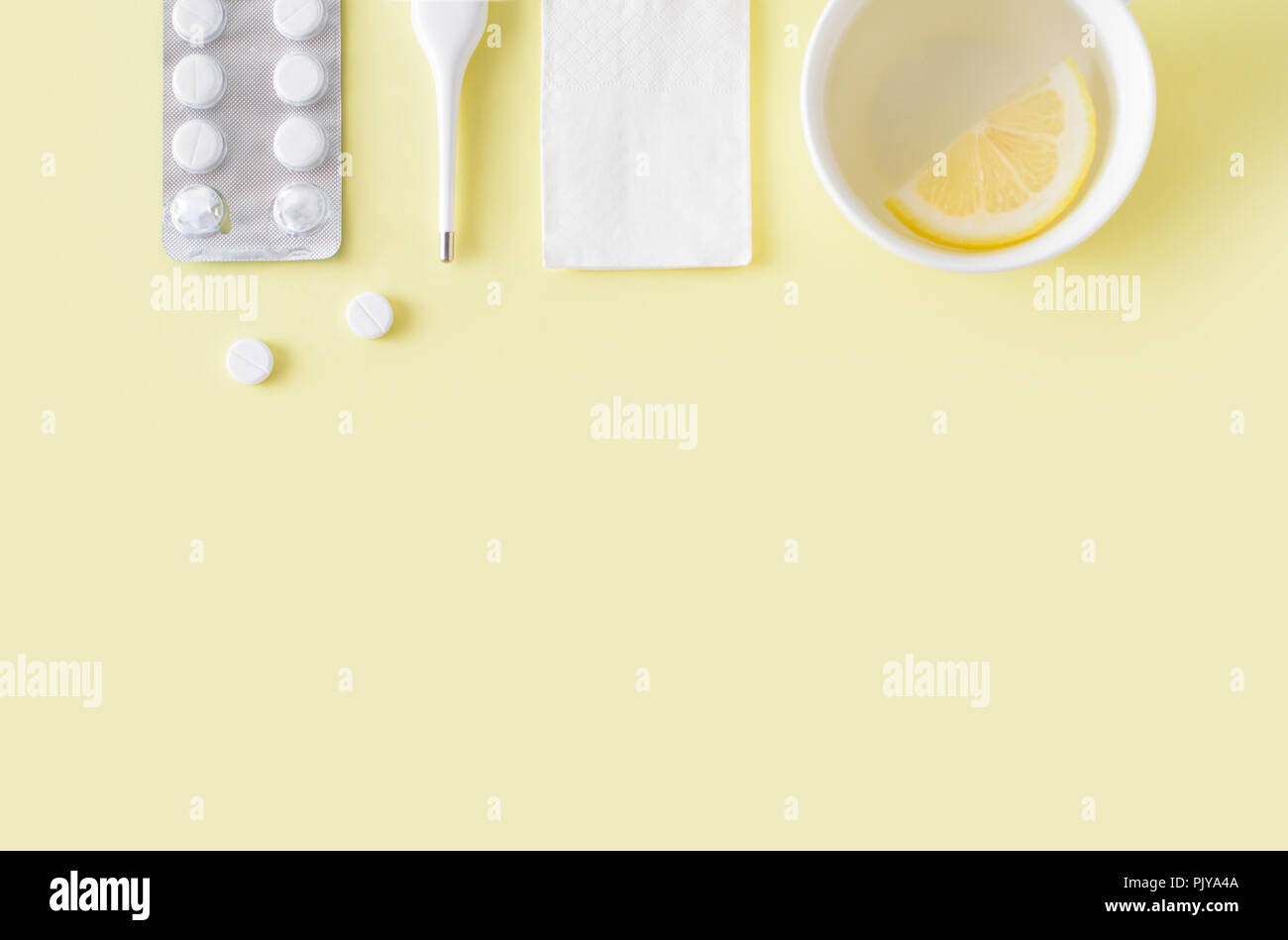 Comprimés, un thermomètre et une tasse de thé sur fond jaune. Le traitement du rhume et de la grippe. Mise à plat, vue du dessus. Copie gratuite de l'espace. Banque D'Images