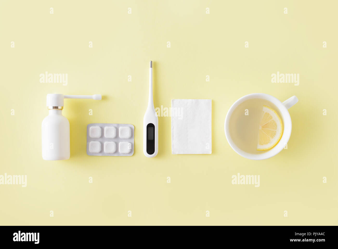 Le traitement du rhume et de la grippe. Comprimés, spray gorge, thermomètre, tasse de thé au citron simple sur fond jaune. La thérapie de soins de santé. Télévision lay, top vi Banque D'Images