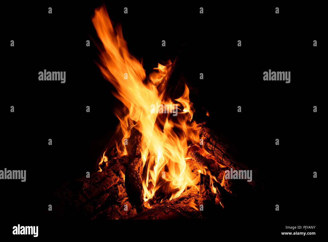 Jaune, rouge et orange des jaillissements de flammes, de charbon et de bois de chauffage dans un incendie d'un feu sur un fond noir Banque D'Images