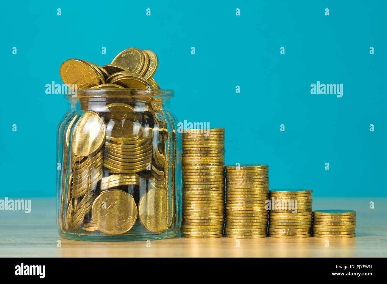 Les piles de pièces de monnaie d'or et d'argent dans le bocal en verre sur la table avec un fond vert, pour l'épargne pour l'avenir d'avion finances concept idée. Banque D'Images