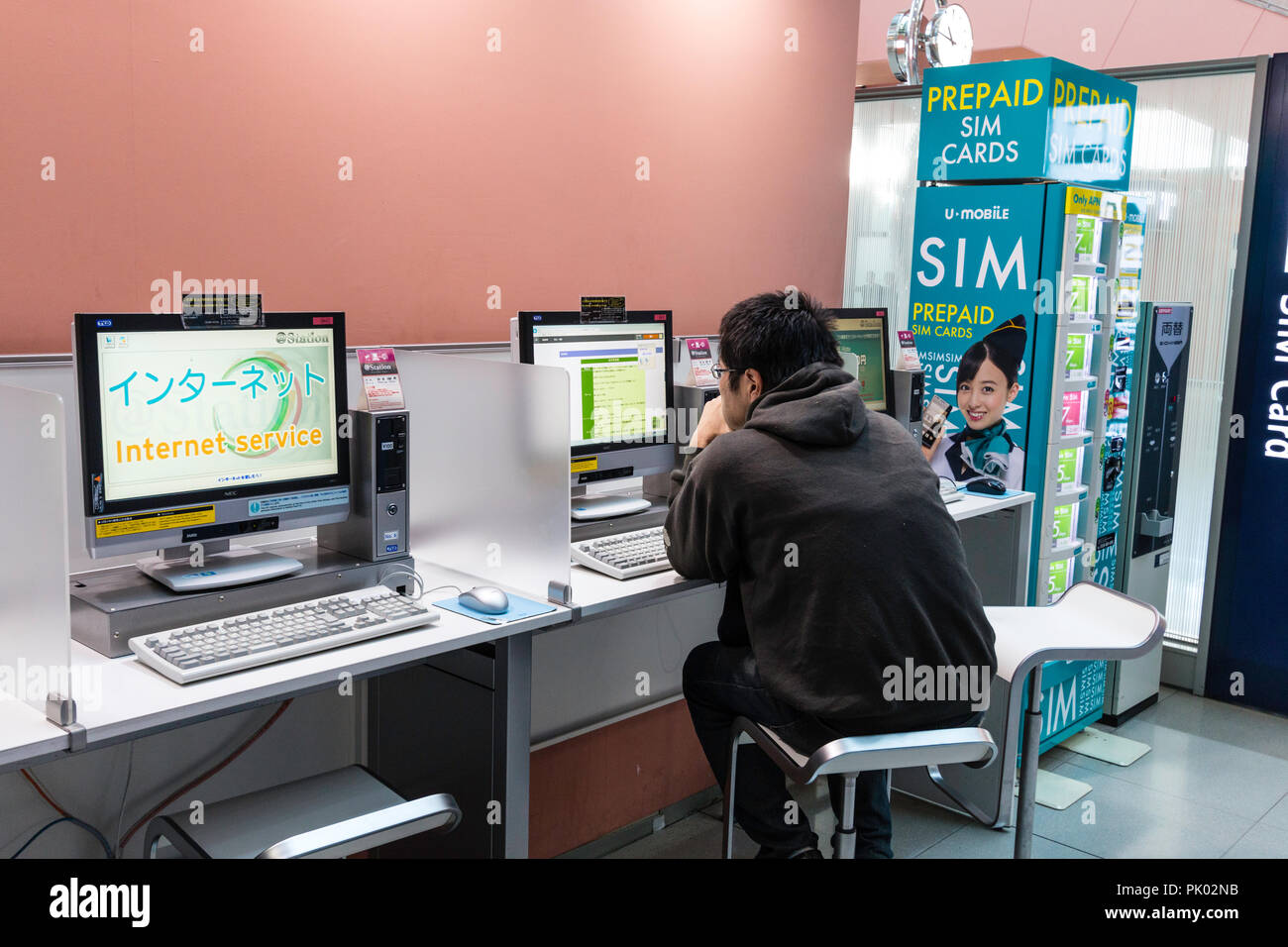 Japon, Osaka. L'Aéroport International de Kansai. KIX, une borne d'intérieur rez-de-chaussée, zone d'arrivée. L'homme à l'aide d'internet sur l'aéroport le terminal d'ordinateur. Banque D'Images