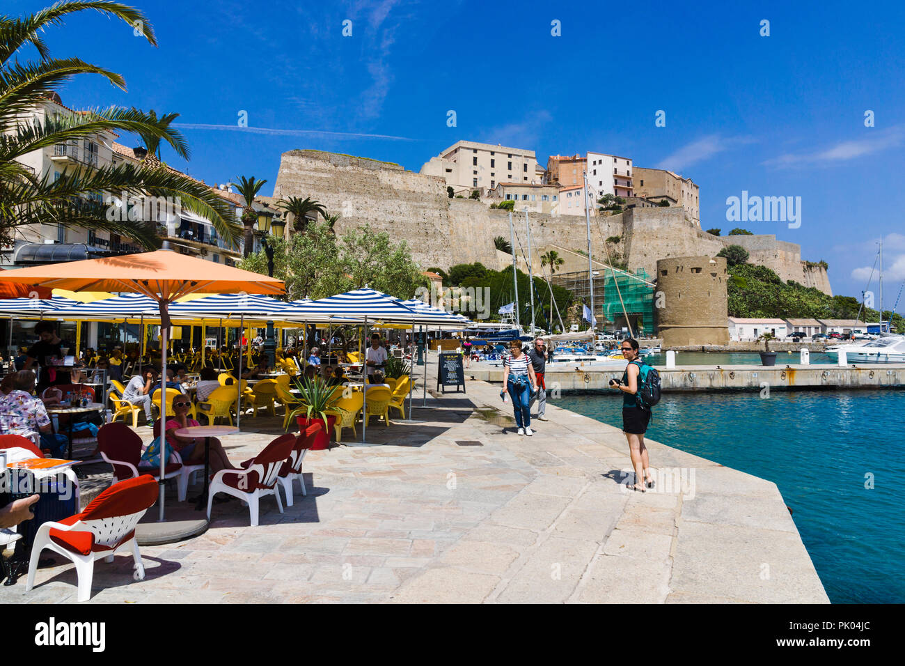 Restaurants au bord de l'eau, la citadelle en arrière-plan. Calvi, Corse, France Banque D'Images