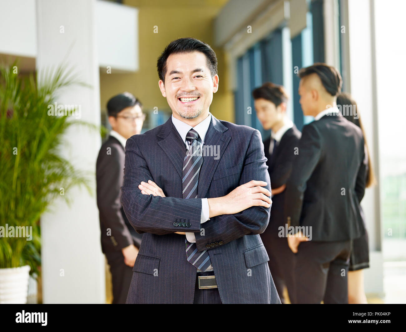 Portrait of a senior business manager arms crossed looking at camera avec un grand sourire. Banque D'Images