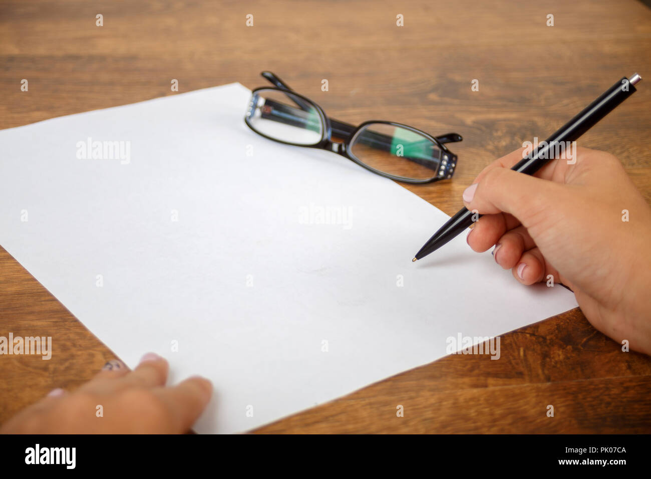 Remplissez le formulaire à la main sur un format a4 feuille verticale sur table en bois avec Glases dans l'arrière-plan Banque D'Images
