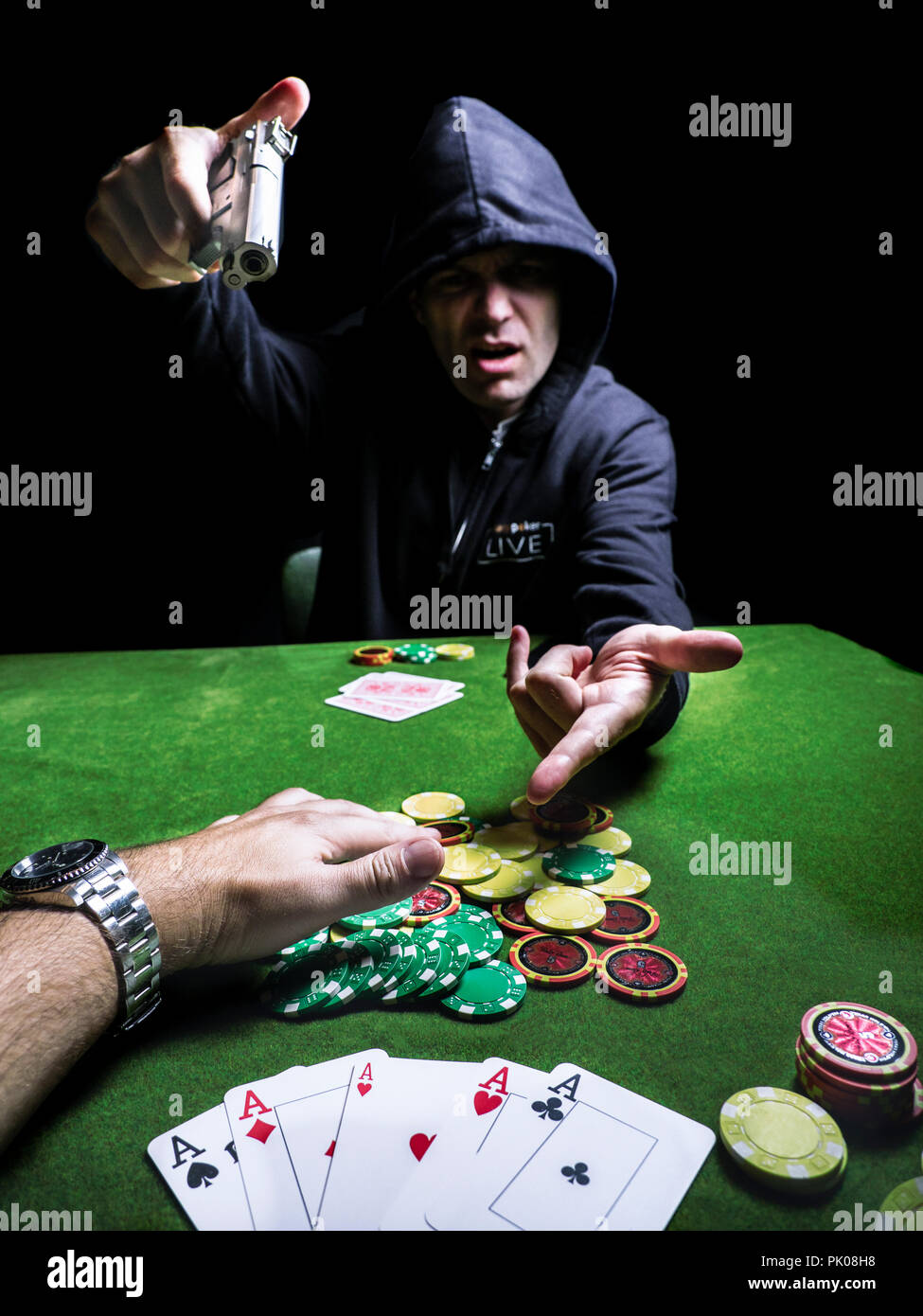 Joueur de poker en colère contre braquer une arme de poing prohibée cheater tricher cartes jeu de cartes plaquettes hoodie Banque D'Images