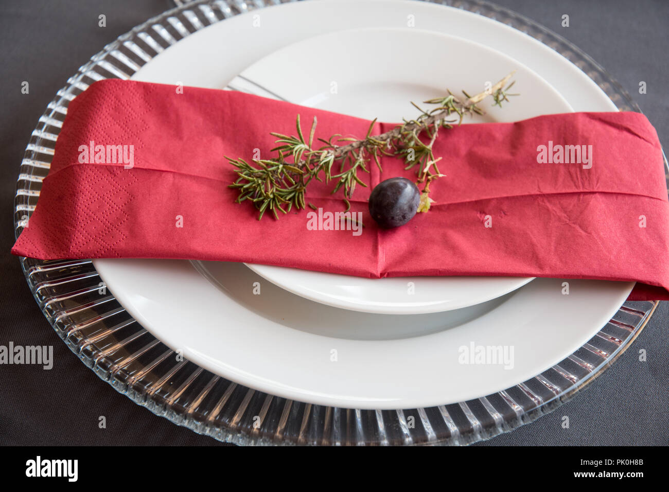 La table du déjeuner ensemble avec des plaques en gris et blanc, de belles assiettes, serviette rouge, petite branche d'arbre décoratif, deux cépages avec décor de fruits et fleurs Banque D'Images