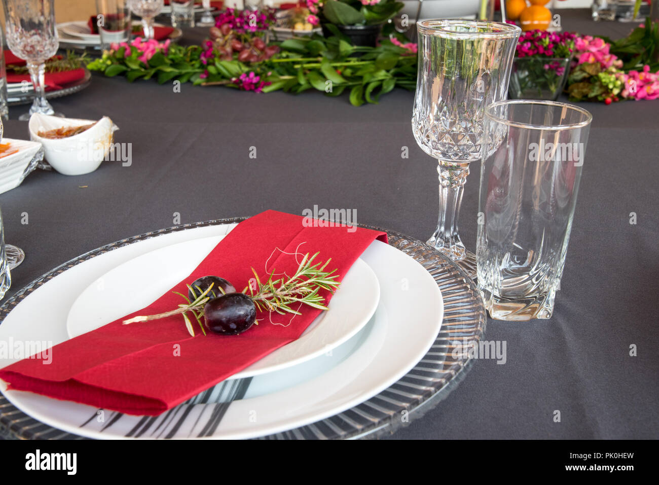 La table du déjeuner ensemble avec des plaques en gris et blanc, de belles assiettes, serviette rouge, petit arbre décoratif,direction des deux cépages avec décor floral et de fruits. Banque D'Images