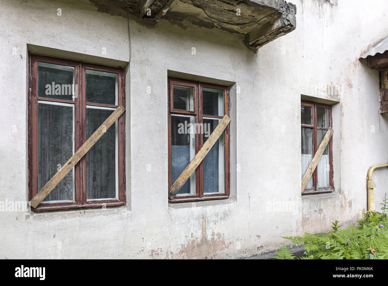 Vieux Mur de stuc blanc maison abandonnée avec barricadèrent windows Banque D'Images