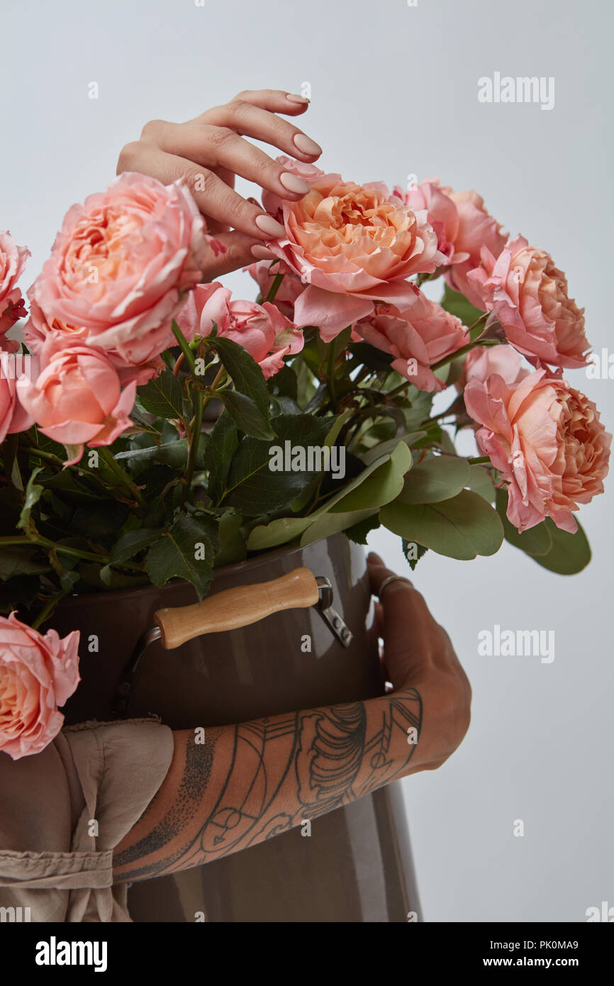 Un gros bouquet de roses roses dans un vase est tenu par les mains de femmes avec un tatouage sur un fond gris. Photo peuvent être utilisés pour l'affichage ou un montage votre EDI Banque D'Images