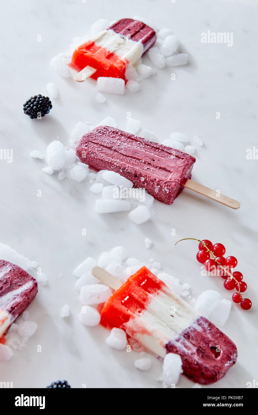 Sucettes glacées aux fruits colorés avec de la glace concassée et de baies plus en arrière-plan. Concept de l'alimentation d'été Banque D'Images