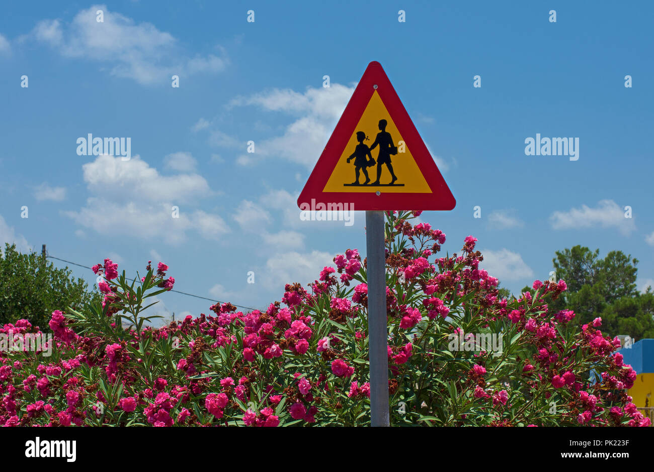 Triangle de signalisation "Attention enfants" dans la Grèce ensoleillée Banque D'Images