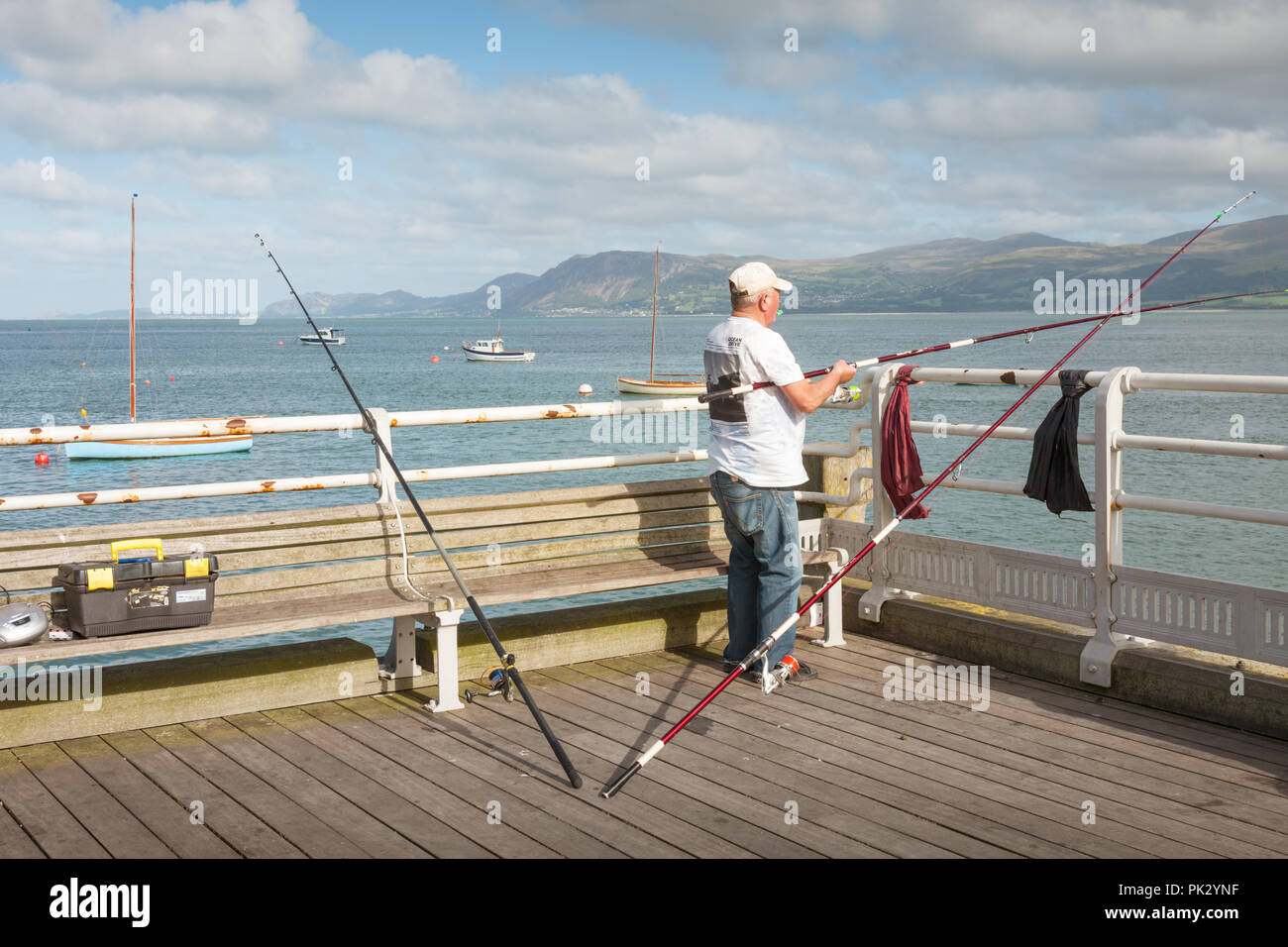 Man la pêche au large de la jetée, Beaumaris, Anglesey, Pays de Galles UK Banque D'Images